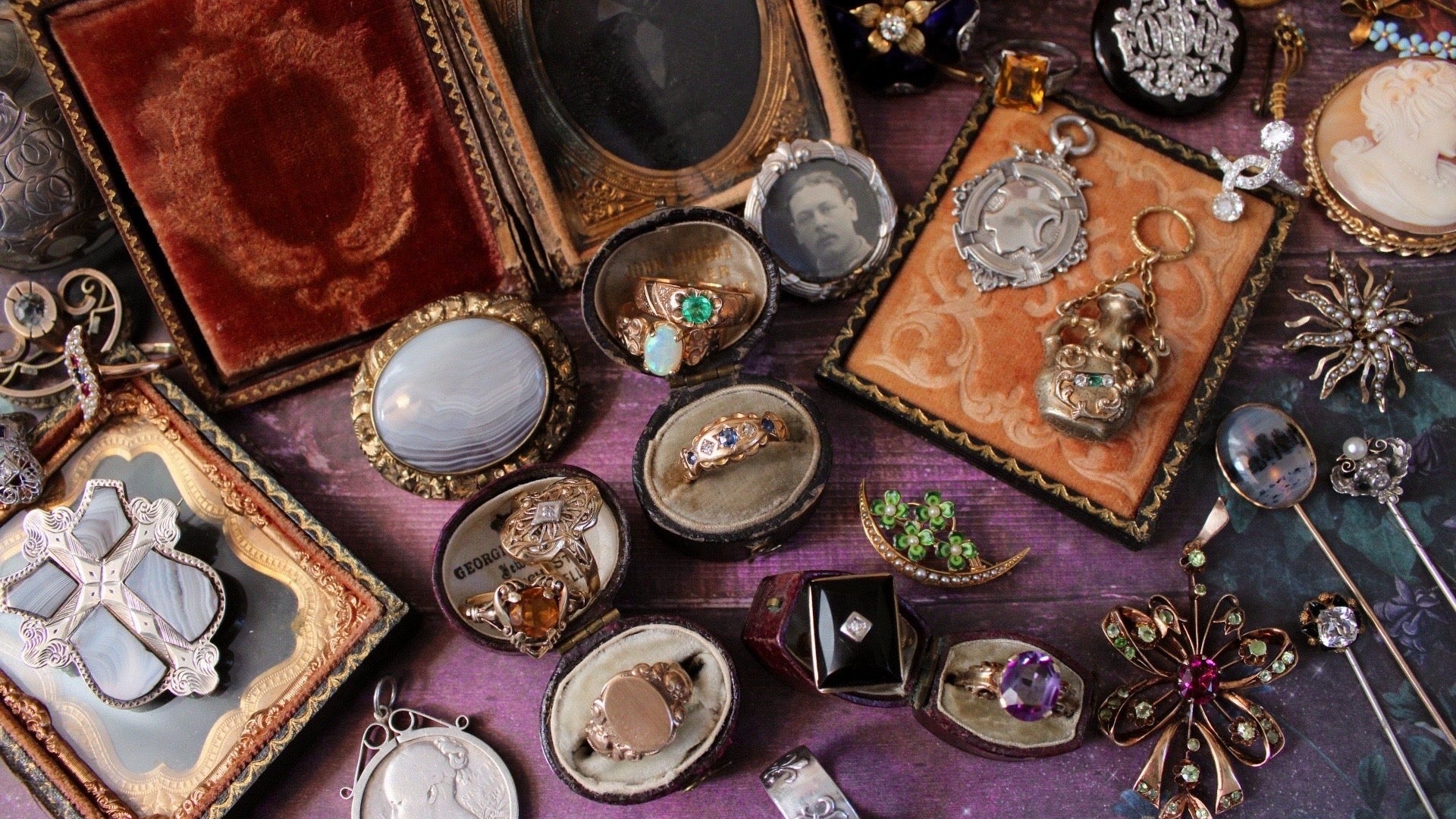 Collection of vintage jewelry including brooches and rings on a textured surface