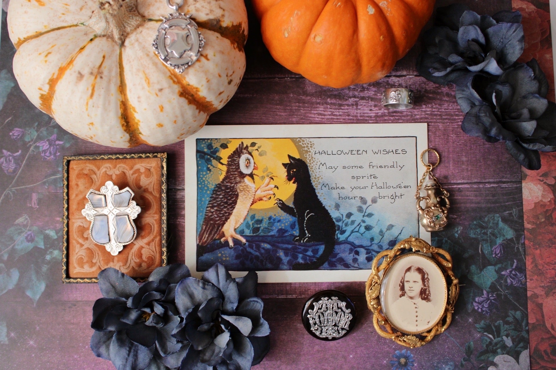 Decorative items including pumpkins, a card with an owl and cat illustration, and various small objects on a textured surface.