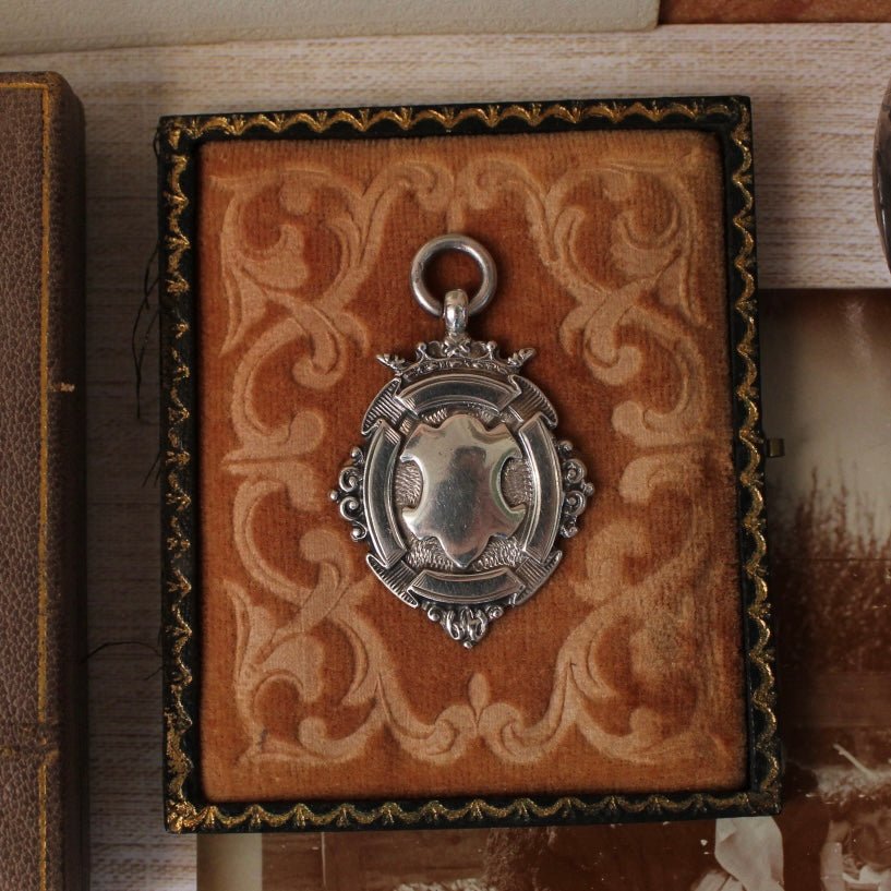Silver pendant on a decorative brown box with intricate patterns