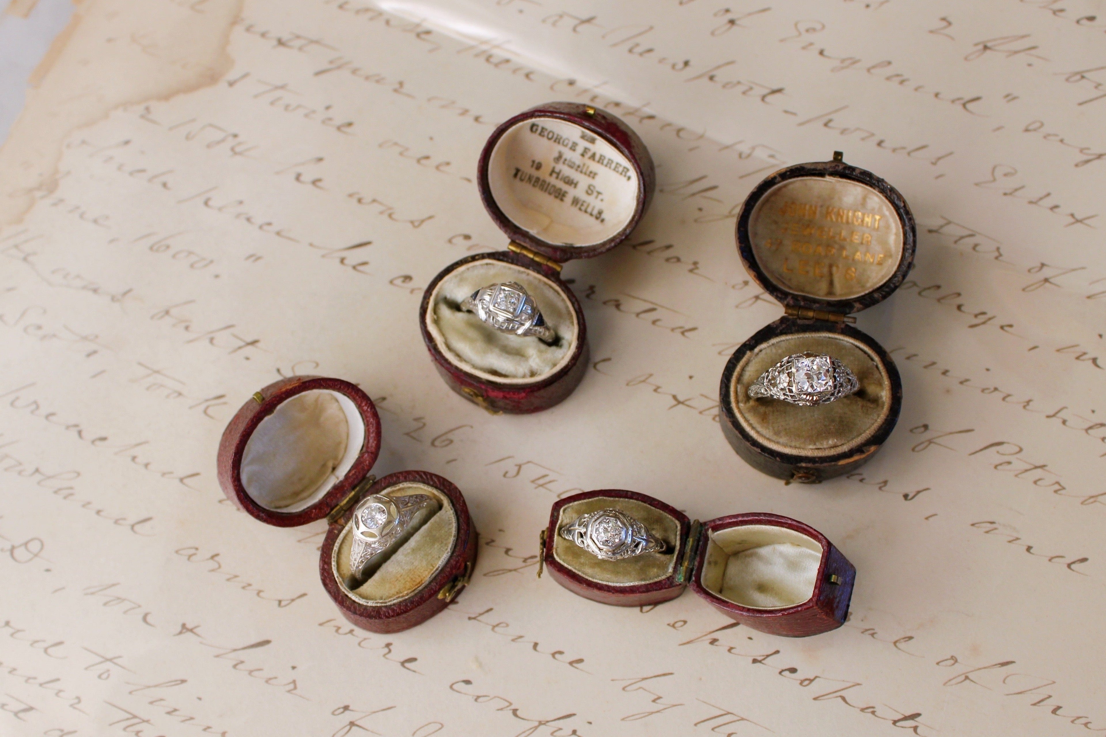 Set of diamond rings in open wooden boxes on an old letter.
